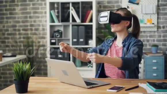 玩虚拟现实眼镜的女孩在办公室里移动手臂视频的预览图