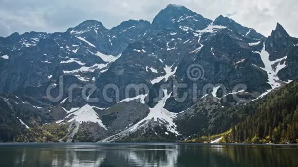 有冷蓝水高山森林和雪岩背景的山湖视频的预览图