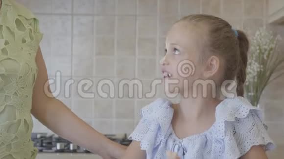美丽的年轻妈妈和小可爱的女儿一起在厨房做饭家庭幸福妈妈吻了一个女孩视频的预览图