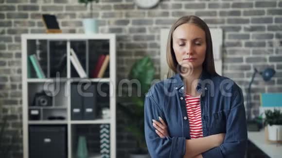 两臂交叉站在办公室的漂亮年轻女子的画像视频的预览图