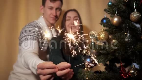 快乐的一对穿着毛衣的情侣在镜头前手持明亮的火花视频的预览图