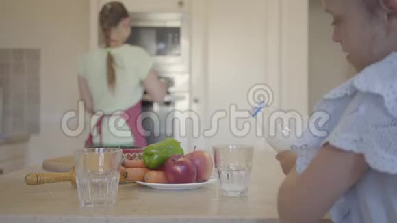 女儿把牛奶倒进杯子里快乐的妈妈在舒适的厨房里从烤箱里拿出刚出炉的面包视频的预览图