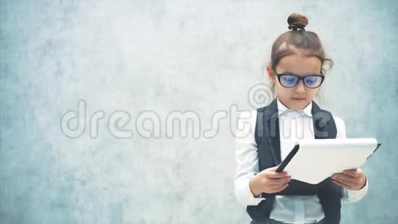 这个小女孩的背景是灰色的在此期间从拥抱她的黑色文件夹中读取信息穿着视频的预览图