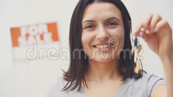 年轻漂亮的女人拿着钥匙微笑着提供房子出售和搬出视频的预览图
