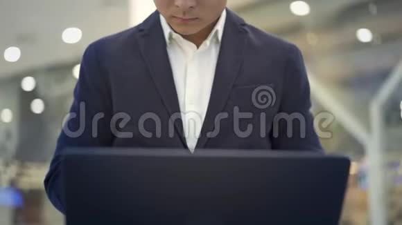 穿着西装膝盖上放着笔记本电脑工作的亚洲男性商人视频的预览图