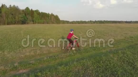 一个年轻的女孩骑自行车在农村的道路上四架直升机射击从上面看视频的预览图