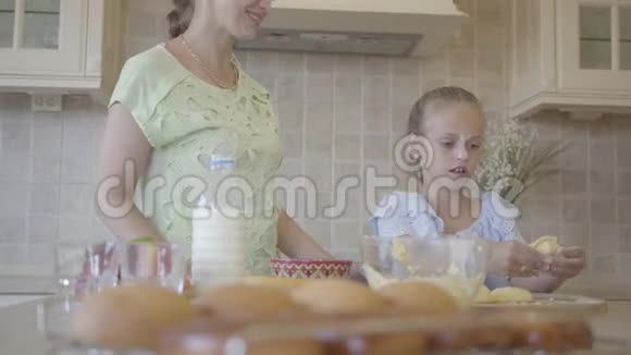 年轻的女人和她的小女儿在家里厨房做蛋糕女孩捏面团妈妈视频的预览图