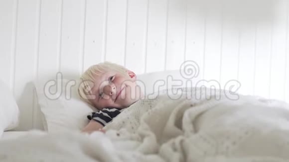 英俊的金发男孩早上躺在床上视频的预览图