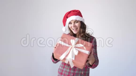 戴圣诞帽的快乐女孩在白色背景上赠送一个礼品盒女人手里的小礼物假日包装视频的预览图