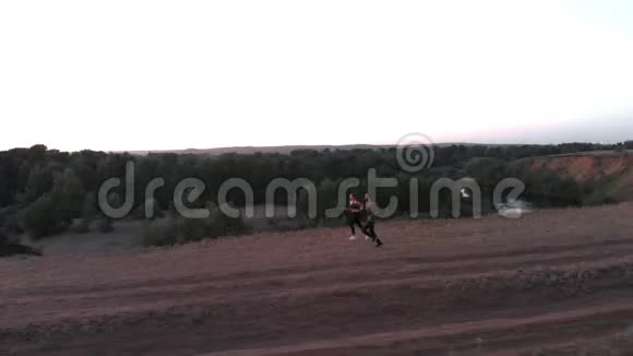 男人和女孩在日落时举行了一场慢跑在你的背景下沿着河底陡峭的悬崖奔跑视频的预览图