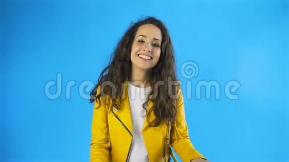 年轻快乐的女人开心地笑着用蓝色背景的手捂着嘴视频的预览图