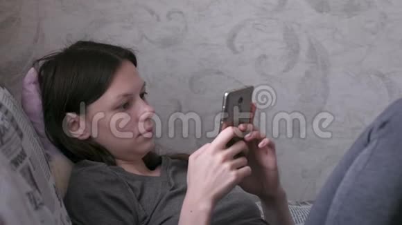 女人躺在沙发上看着手机视频的预览图