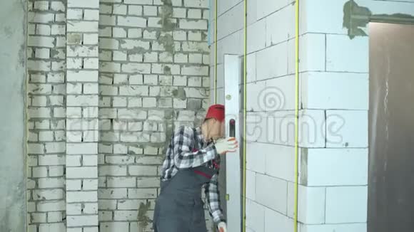 施工人员穿戴红帽用施工尺检查墙体质量视频的预览图