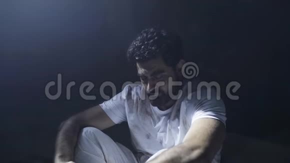 一个被压迫的年轻人坐在黑暗的监狱里视频的预览图