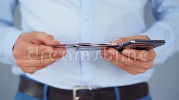 正式穿着的男人从几张信用卡中选择一张信用卡并将其号码输入智能手机以在线支付网上在线视频的预览图