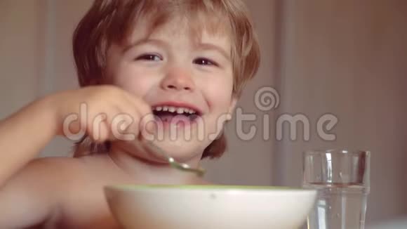 快乐的婴儿用勺子吃食物美丽的孩子在家吃早餐的肖像微笑快乐视频的预览图