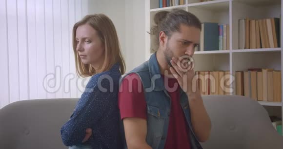 两个愤怒的朋友在争吵中背靠背坐在沙发上女朋友和男朋友之间发生冲突视频的预览图
