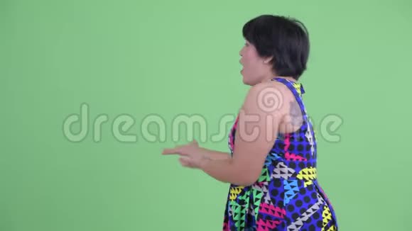 快乐的年轻超重的亚洲女人向后展示看上去很惊讶视频的预览图