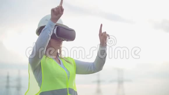 中期计划女性能源工程师在虚拟现实眼镜和白色头盔背景下的高压电力视频的预览图
