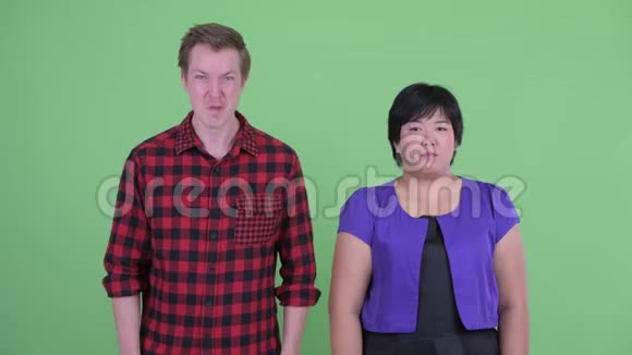 快乐的斯堪的纳维亚时髦男人竖起大拇指超重的亚洲女人看起来很困惑视频的预览图