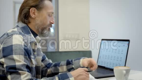 成年帅哥在笔记本电脑咖啡馆工作视频的预览图