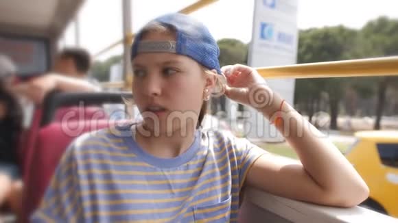 一个戴着棒球帽的伤心少女坐在没有窗户的公共汽车上视频的预览图