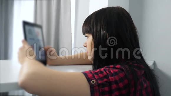 网上购物的概念一个年轻女孩坐在网上商店里看着商品在生活方式上一种数字视频的预览图