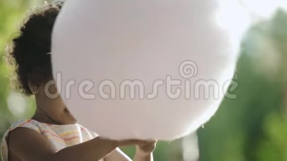 头戴帽子的非裔美国小女孩吃棉花糖视频的预览图