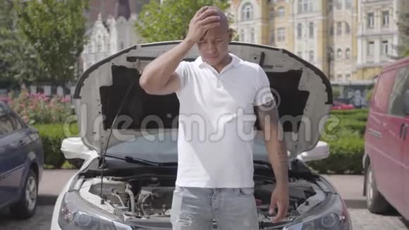 秃顶的中东男子站在车前打开引擎盖手里拿着头坏了的那个人视频的预览图