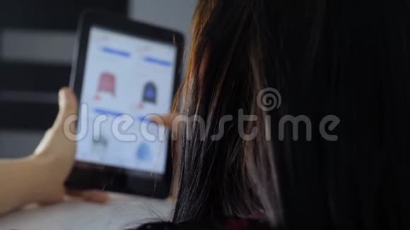 网上购物的概念坐在网上商店看商品的年轻女孩在数字平板电脑上购物妇女视频的预览图
