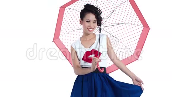 漂亮的亚洲女孩带着一把带有圆点图案的伞在工作室里摆姿势时尚镜头视频的预览图
