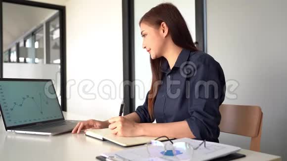 自信美丽的亚洲商界女性在笔记本电脑和工作站文件上从事新创业项目的视频视频的预览图