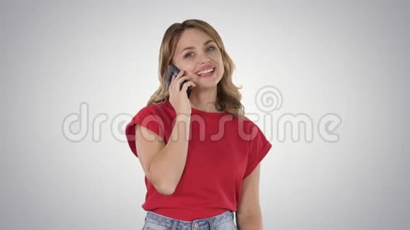 穿红色t恤的年轻美女在梯度背景下的手机上说话视频的预览图