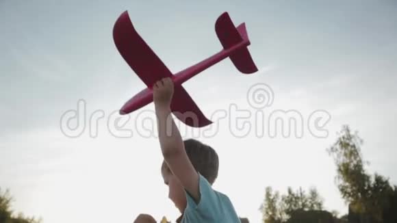 一个小男孩手里拿着一架粉红色玩具飞机跑过田野视频的预览图