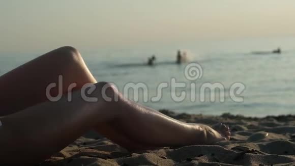 穿泳衣的年轻女子坐在热带海滩上看日落视频的预览图