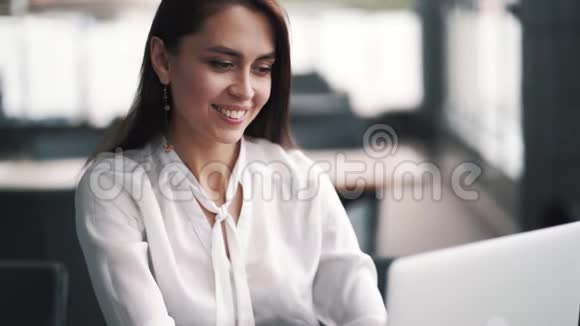 微笑的女商人坐在咖啡馆里的肖像在笔记本电脑上工作慢动作视频的预览图