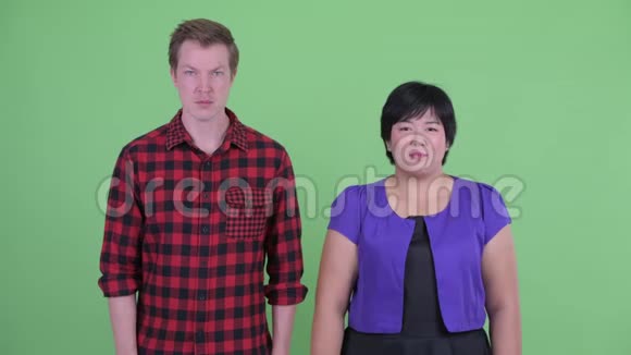 快乐超重的亚洲女人竖起大拇指斯堪的纳维亚时髦男人看起来很困惑视频的预览图