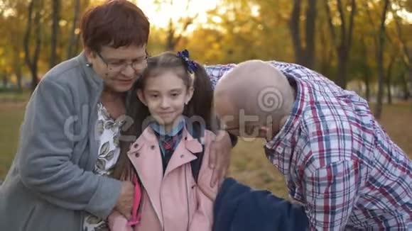 祖父母和孙女在秋天公园散步爷爷奶奶的特写镜头拥抱小孙女视频的预览图