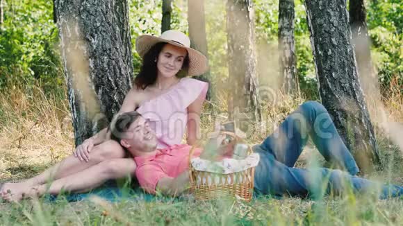 野餐时间快乐的年轻夫妇摆出自拍的姿势男人趴在她的手上公园的户外活动视频的预览图