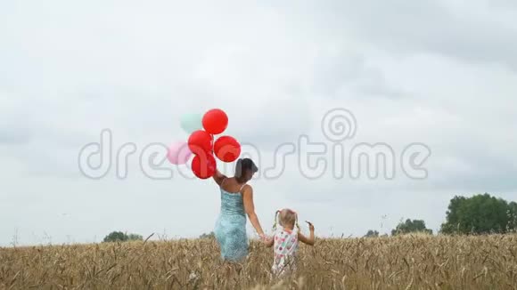 小女孩和妈妈带着气球在田野里视频的预览图