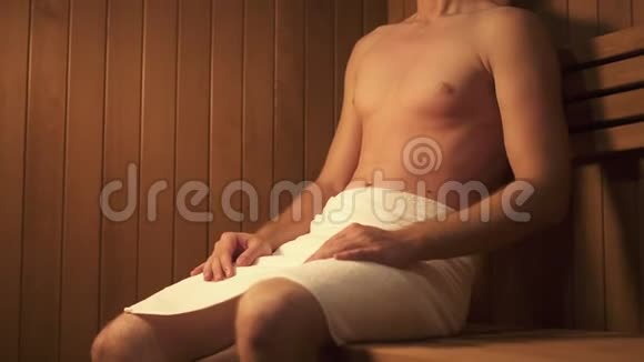 年轻漂亮的男人坐在出汗室的木凳上视频的预览图
