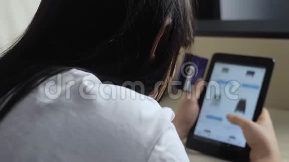女孩制作在线生活方式销售购物概念与数字平板电脑黑发女人躺在沙发上看网上商店视频的预览图