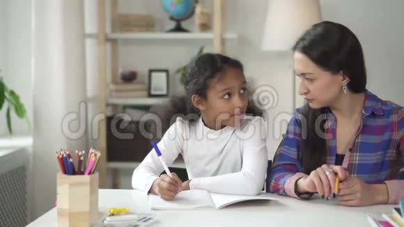 女儿拿着笔在妈妈的帮助和支持下学习妈妈老师视频的预览图