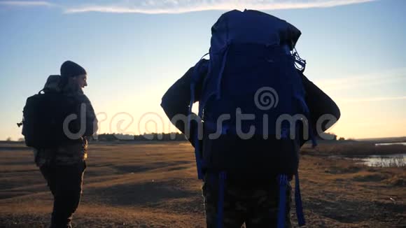 两位生活方式的游客一起背着背包慢动作行走在阳光的照射下走着剪影视频的预览图