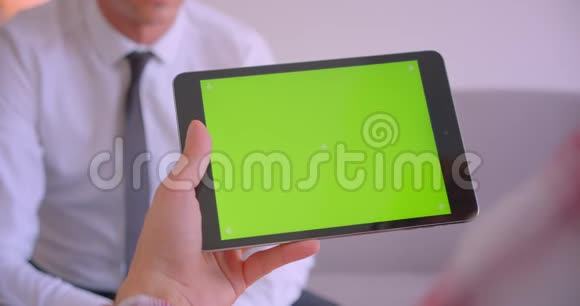 商家与合作伙伴平板电脑对话的特写肖像办公室里有绿色彩色钥匙屏视频的预览图