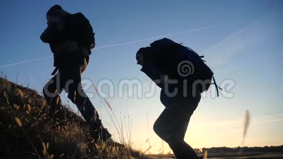 两名游客带着背包慢动作的生活方式走着走着在阳光的照射下剪影视频的预览图