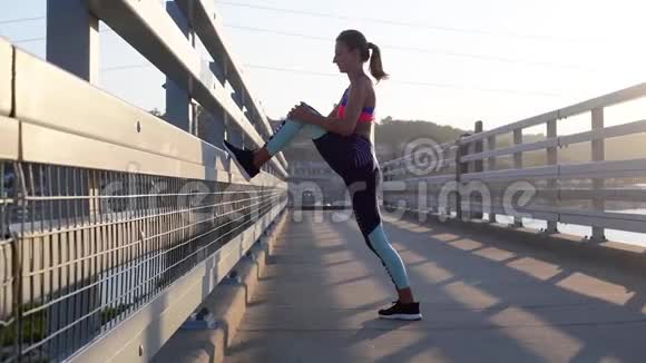 运动妇女在跑步前伸展双腿年轻女子做早操视频的预览图