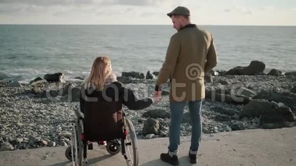 可爱的一对站在海岸上残疾的女人和健康的男人向后看视频的预览图
