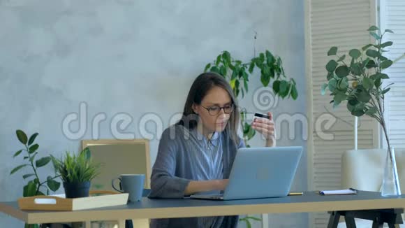 女性在室内刷卡购物白天使用笔记本视频的预览图