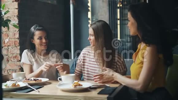 美丽的年轻女子携手在现代咖啡馆里欢笑视频的预览图